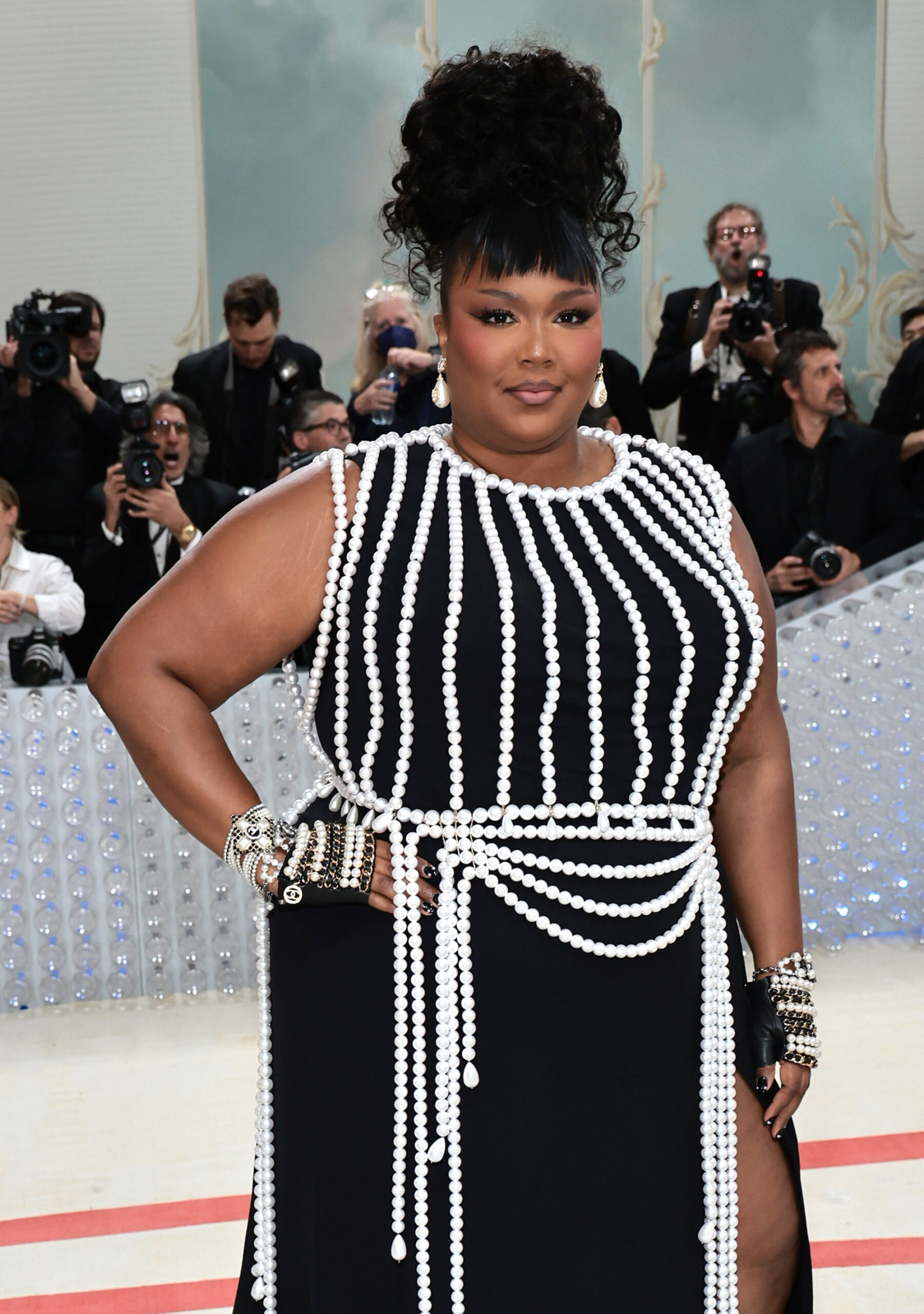 LIZZO, American singer, wore a custom a black silk crêpe dress with a glass pearls harness, inspired by look 129, from the Fall-Winter 1991/92 Ready-to-Wear collection. CHANEL accessories, shoes and bag.